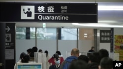 从中国武汉和其他城市飞抵日本成田国际机场的旅客接受体温检测。(2020年1月23日)