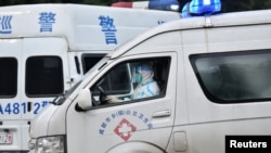 资料照:中国四川成都一名医护人员身穿防护服驾驶救护车。(2020年12月9日)
