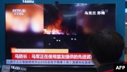 资料照 - 2022年2月25日,一位居民在中国东部浙江省杭州市的一家购物中心在电视屏幕上观看播放俄罗斯和乌克兰冲突的新闻。