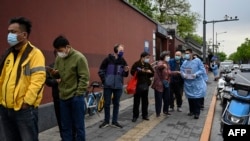 北京从4月26日开始对2千1百万北京居民大规模新冠病毒检测。图为4月27日,人们在一座临时检测站外排队等后检测。
