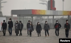 日本游客带着口罩在浓重的雾霾中走向北京的奥林匹克公园(2014年2月25日)