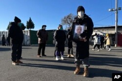 北京一家火葬场外死者亲属手捧亲人的照片。(2022年12月17日)
