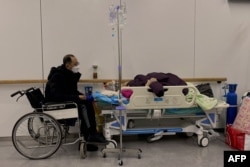 天津南开医院里一名坐轮椅的男子守护一名感染新冠的病人。(2022年12月28日)