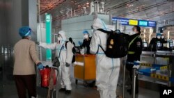 身穿防护服的防疫人员在北京首都机场给旅客指导行走方向(美联社2022年12月13日照片)
