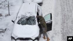 美国艾奥瓦州一名男子在清除汽车上的积雪。(2022年12月22日)