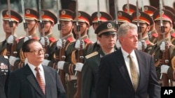 美国前总统克林顿和中国前国家主席江泽民1998年6月27日在北京人民大会堂东面为克林顿访华举行欢迎仪式。(资料照)