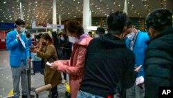 北京国际机场的工作人员在帮助从海外抵达的乘客填写新冠健康状况表格。(2023年1月9日)