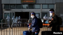 2022年3月14日,在香港爆发新冠毒病期间,戴着口罩和防护罩的旅客通过在深圳湾口岸的中港边境