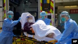 香港医护人员将一位新冠病人从救护车上抬下送入医院。(2022年3月4日)