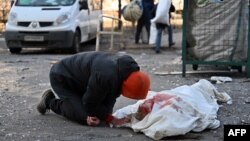 乌克兰首都基辅一市民跪在俄军轰炸公寓楼而死亡的一具尸体旁。(2022年3月17日)