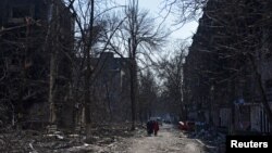 乌克兰马里乌波尔市居民走过被炮火摧毁的居民建筑(2022年3月18日)