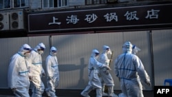 身穿防护服的防疫人员在上海一处因发现新冠疫情而被封闭的小区的屏障外。(2022年3月15日)