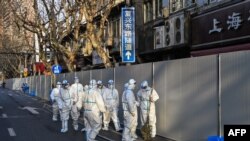 身穿防护服的工作人员在上海一处因发现新冠疫情而被封闭的小区的屏障外。(2022年3月15日)