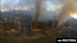 2022年3月14日,乌克兰马里乌波尔发生爆炸,鸟瞰图显示受损住宅楼冒出浓烟。这张静止图像是从社交媒体获取的无人机镜头中拍摄的。