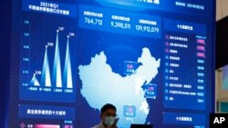 资料照:2021年4月30日,在北京的一个互联网博览会上,一名男子在显示大数据和中国地图的巨型显示器附近用手机说话。(美联社)