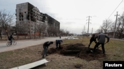 People dig a grave for victims killed during Ukraine-Russia conflict in a street in the besieged southern port city of Mariupol, Ukraine March 20, 2022. (Alexander Ermochenko/REUTERS)