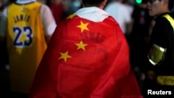 中国上海,在NBA布鲁克林篮网队和洛杉矶湖人队的表演赛之前,一名身穿勒布朗·詹姆斯球衣的男子在梅赛德斯-奔驰球场外用中国国旗包裹自己(2019年10月10日)。