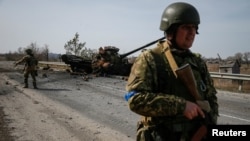 A Ukrainian serviceman stands near the wreck of a Russian tank on the front line in the Kyiv region, Ukraine, March 28, 2022.