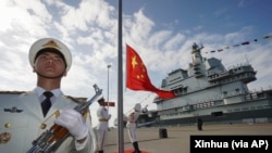 中国航母山东号停泊在海南省的一个海军基地,士兵在举行升旗仪式。(资料照:2019年12月17日)