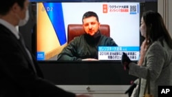 日本民众走过街头正在播放乌克兰总统泽连斯基对日本国会在线演讲实况的电视屏幕。(2022年3月23日)
