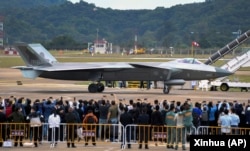 在第14届珠海航空航天展览会上,中国制造的歼-20重型隐身战斗机停在跑道上供参观者拍照。(2022年11月8日)