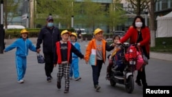 北京一所小学校的家长在接放学的孩子回家。(2021年4月6日)