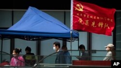 人们在北京市东城区插着一面中共旗帜的新冠病毒核酸检测点排队等候检测。(2022年4月29日)