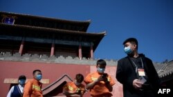 人们在北京紫禁城旁的一个新冠病毒核酸检测点旁排队等候进行检测。(2022年5月1日)