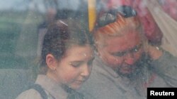 People are seen through a bus window as civilians from Mariupol, including evacuees from Azovstal steel plant, travel in a convoy to Zaporizhzhia, during Ukraine-Russia conflict in the Donetsk Region, Ukraine, May 2, 2022.