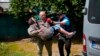 A woman is carried from her home in an evacuation by volunteers of Vostok SOS charitable organization in Bakhmut, eastern Ukraine, May 27, 2022.