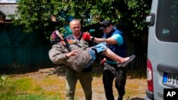 A woman is carried from her home in an evacuation by volunteers of Vostok SOS charitable organization in Bakhmut, eastern Ukraine, May 27, 2022.