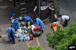 身穿防护服的人员在上海静安区给封在小区里的居民发放食物。(2022年5月8日)