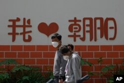 北京朝阳区两个带着口罩的居民去排队做新冠核酸检测。(2022年5月11日)