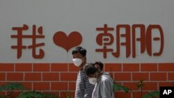 北京朝阳区两个带着口罩的居民去排队做新冠核酸检测。(2022年5月11日)