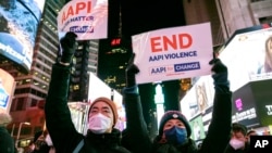 资料照片:2022年1月18日,人们在纽约时报广场举着支持亚裔太平洋岛民社区的标语,参加纪念地铁袭击事件受害者米歇尔·阿丽莎·戈 (Michelle Alyssa Go) 的烛光守夜活动。(美联社照片)