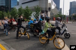 上海市民和快递小哥骑着车在街头等交通灯。(2022年5月31日)