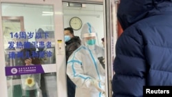 2022年12月15日,一名男子在北京一家医院的发热门诊门外排队等待。一位身着防护服的医务人员正准备关门。中国有关当局毫无预兆地宣布解封后,新冠肺炎的感染人数和死亡人数不断增加,引起人们的恐慌。
