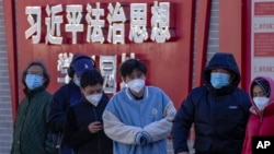 北京市民在宣传习近平思想的标语墙前排队等候进行核算检测。(2022年12月5日)