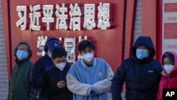 北京市民在宣传习近平思想的标语墙前排队等候进行核酸检测。(2022年12月5日)