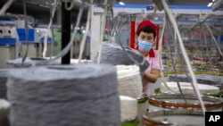 资料照片:在官方为外国记者组织的一次参观活动中,一名工人在中国新疆维吾尔族自治区阿克苏的一家纺织厂收集棉线团。(2021年4月20日)