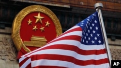 美国国旗,背景为中国国徽。(美联社照片)