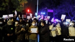 2022年11月28日,在中国北京,随着新冠肺炎疫情的持续,人们在为乌鲁木齐火灾遇难者守夜后,手持白纸抗议新冠肺炎疫情限制措施。