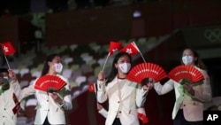 资料照 - 2021年在东京举行的2020东京夏季奥运会开幕式上,香港代表队队员手举香港区旗和印有“香港·中国”英文字的红色扇子走进场内。