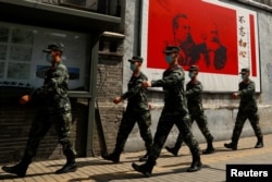 资料照:中国武警士兵走过北京街头一幅马克思恩格斯画像及写有“不忘初心”的宣传画。(2020年5月22日)