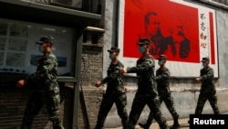 资料照:中国武警士兵走过北京街头一幅马克思恩格斯画像及写有“不忘初心”的宣传画。(2020年5月22日)