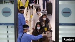 身穿防护服的韩国军人指引从中国抵达仁川国际机场的乘客进行新冠核酸检测。(2023年1月4日)