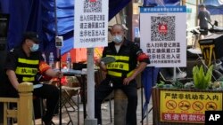 两名执勤保安在北京一个居民小区外检查居民需要出入小区的健康码。(2022年11月9日)