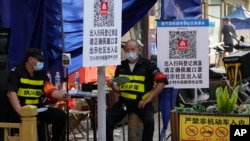 资料照:两名执勤保安在北京一个居民小区外检查居民需要出入小区的健康码。(2022年11月9日)