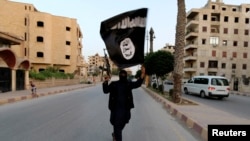 ISIS အကြမ်းဖက်အဖွဲ့ဝင်နဲ့ IS အလံ (REUTERS/Stringer)