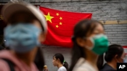 2022年10月1日,北京国庆假期的第一天,人们走在悬挂中国国旗的一条旅游购物街上。